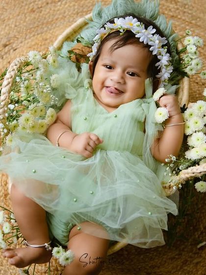 Another joyful shot of the baby girl in her green dress, sticking her tongue out playfully.