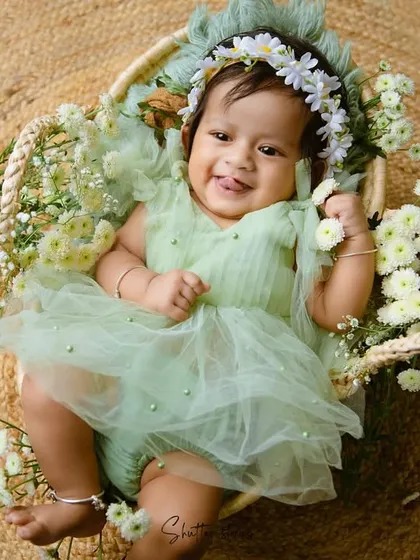 Another joyful shot of the baby girl in her green dress, sticking her tongue out playfully.