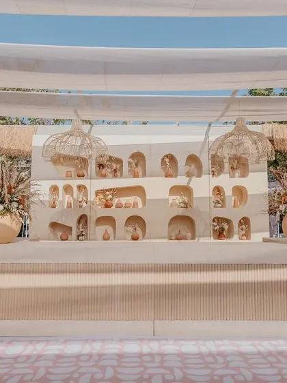 The main backdrop for the Haldi ceremony, featuring a custom-built wall with multiple arches and niches for displaying small decorative items, flanked by large urns with floral arrangements.