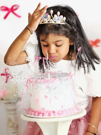 Making a wish. This magical shot captures a little girl blowing glitter from her birthday cake during her princess-themed fifth birthday photoshoot.