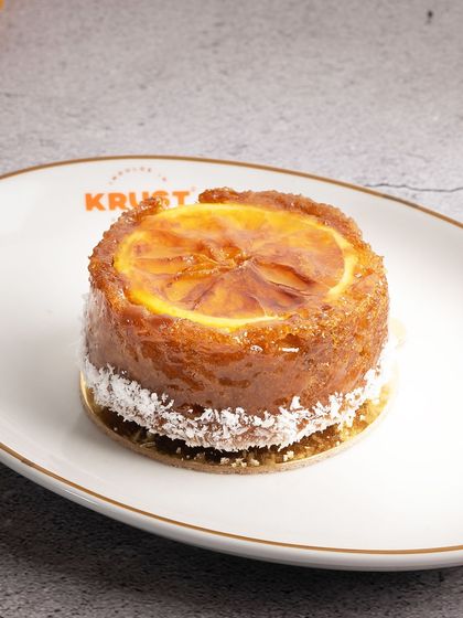 A close-up of the Orange Ginger Tea Cake, highlighting the glistening candied orange slice. This pastry is a feast for the eyes and the palate.