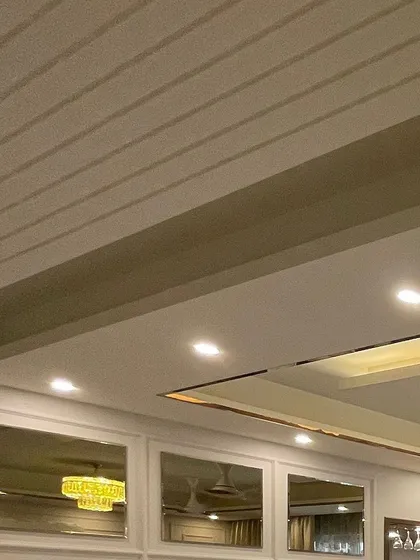 A detail shot of the ceiling, showing the grooved paneling and the metal inlay in the false ceiling. These subtle details contribute to the overall polished look of the home.