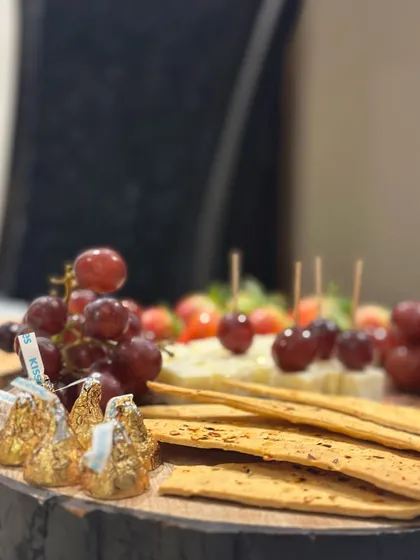 A close-up of a simple yet elegant platter perfect for a cozy get-together. It includes crisp crackers, fresh grapes, cheese, and chocolate kisses for a touch of sweetness.