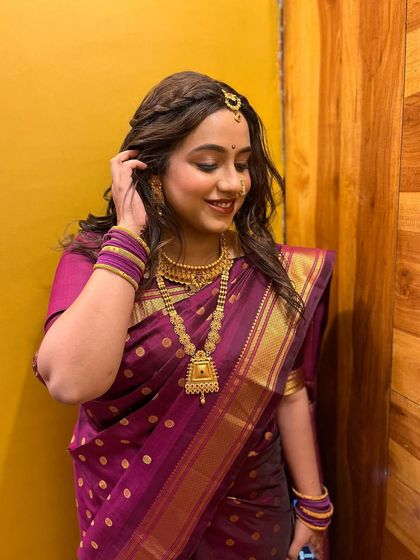 The complete look for Vishakha, featuring a beautiful purple saree and gold jewelry. The makeup is natural and enhances her youthful glow.