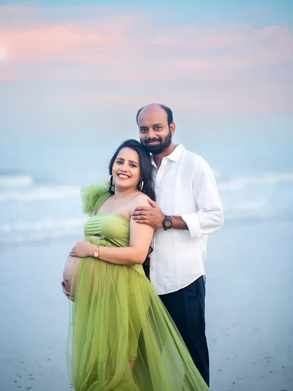 A beautiful portrait of the expecting couple, smiling and radiant against the calming waves.