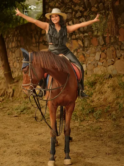 A model in a western-inspired outfit sits atop a horse, exuding joy and confidence. Our horses are calm and well-trained, making them excellent partners for photoshoots.