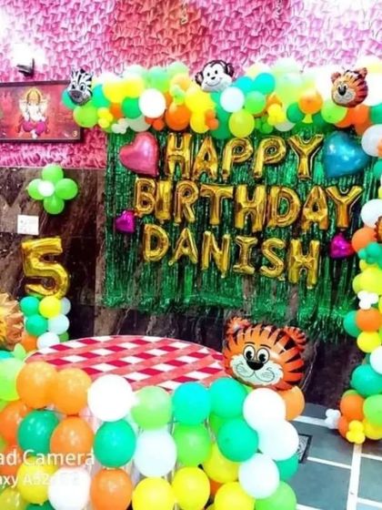 A bright and colorful jungle theme for a 5th birthday. This setup includes a balloon-wrapped table, perfect for cake cutting.