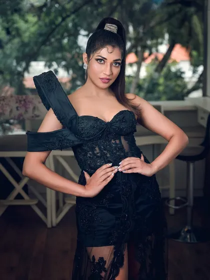 A full-length shot of actress Iti Acharya in an elegant black gown. This photo highlights the dress's unique design and is suitable for fashion features or red carpet-style portfolios.