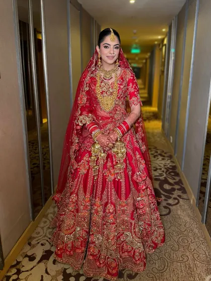 A full view of this stunning red and gold bridal look. The makeup is designed to be harmonious, with glowing skin and defined eyes that stand out beautifully.