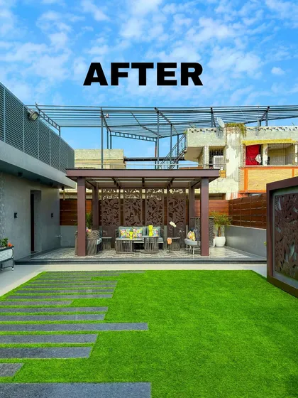 This "after" shot reveals a spacious and elegant terrace design. A large artificial lawn is complemented by a covered seating area under a pergola with intricate jaali screens.