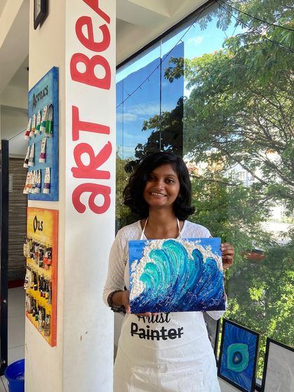 A participant with her finished texture painting of a wave. The 3D effect of the wave crest is created using special texture paste.