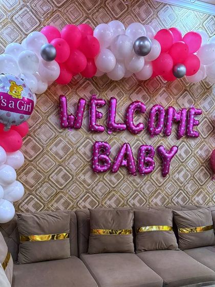 The main balloon arrangement for the welcome home party. The half-arch is created with white, silver, and different shades of pink balloons, with an "It's a Girl" foil balloon as a centerpiece.