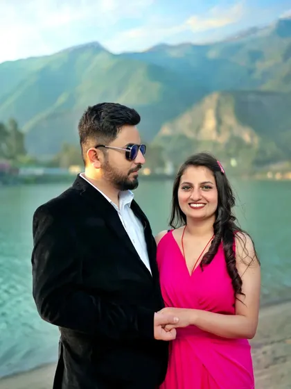 A candid and happy portrait of a couple by the water, with the mountains of Himachal in the background. This shot captures a simple, joyful moment during their pre-wedding shoot.