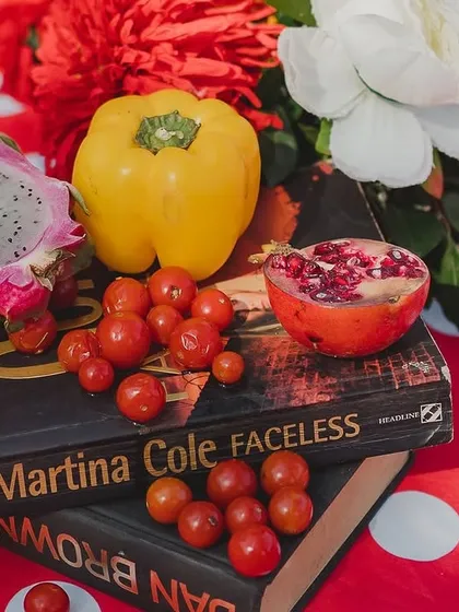A unique centerpiece using books as a base for an arrangement of dragon fruit, cherry tomatoes, and bell peppers. This quirky detail adds personality and charm to the table setting.