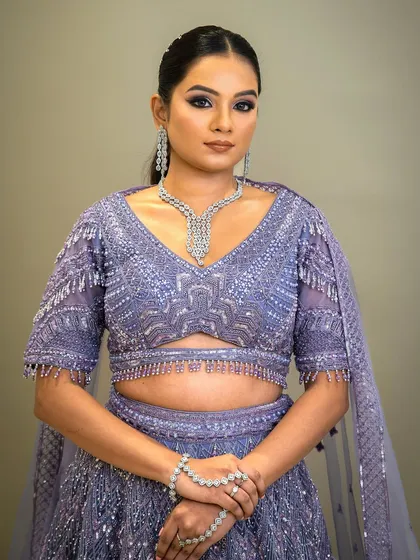 A full view of a model in a stunning lavender lehenga. The zircon necklace and matching bracelet add a layer of sparkle, making this a perfect outfit for a cocktail party or reception.