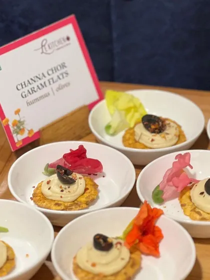 Channa Chor Garam Flats, a creative appetizer combining the crunch of the classic Indian snack with creamy hummus on a cracker.