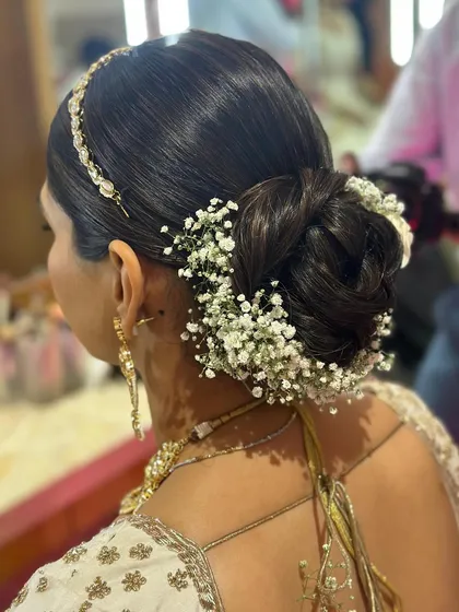 A classic bridal bun wrapped in baby's breath, also known as a gajra bun. This is a timeless and popular choice for traditional Indian weddings.
