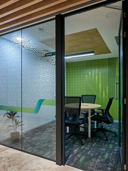 A meeting room with a vibrant green graphic wall and frosted glass for privacy. The design is modern and energetic.
