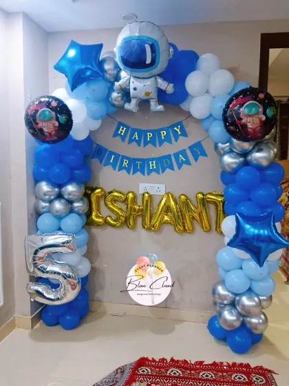 An astronaut-themed balloon arch for a 5th birthday, featuring blue, white, and silver balloons with character foils.