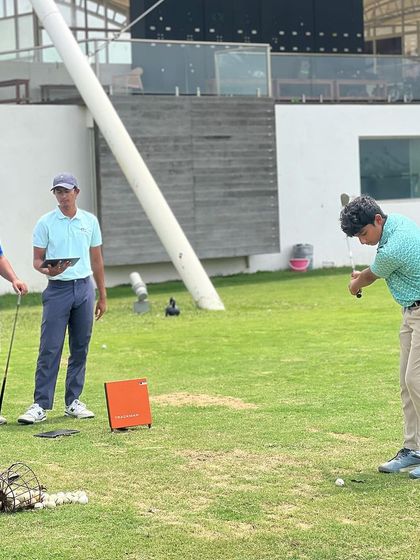 A group of coaches works with a player on the range. This is what teamwork looks like in a high-performance environment.