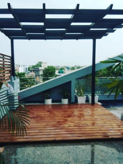 The thermopine wood deck after a rain shower, highlighting the beautiful color and grain of the wood under the modern black pergola.