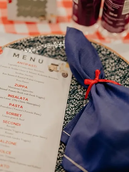The menu for the Italian-themed gala dinner, complete with a custom illustration and a napkin tied with a simple red ribbon. Every detail was designed to enhance the 'la dolce vita' experience.