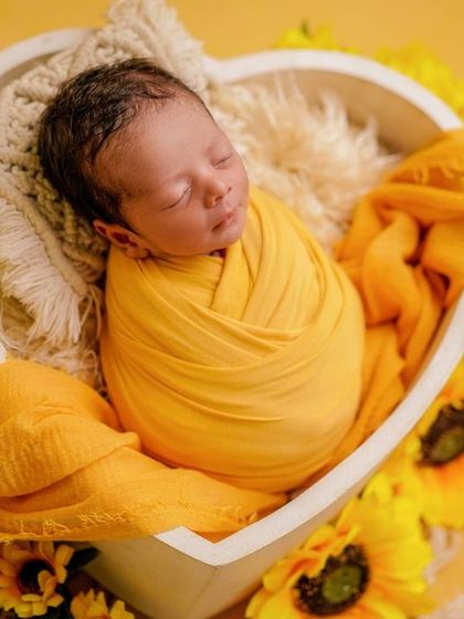 A little ray of sunshine. This baby, swaddled in yellow and surrounded by sunflowers, is the picture of happiness.