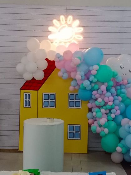 A cute Peppa Pig theme, with a prop of Peppa's house and a pastel colored balloon garland representing clouds and the sun.