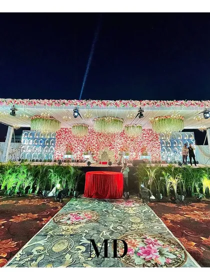 A night view of a grand floral wedding stage we constructed. The combination of a dense floral backdrop, hanging floral chandeliers, and professional stage lighting creates a stunning focal point for the event.