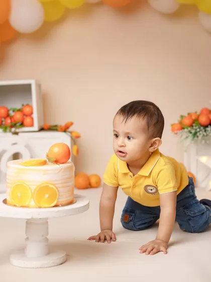 The adventure begins! A little boy crawls towards his orange-themed birthday cake, ready for some messy fun.