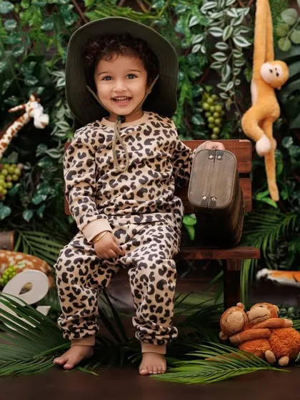 Welcome to the jungle! A happy little explorer in a leopard print outfit is ready for his first birthday adventure.