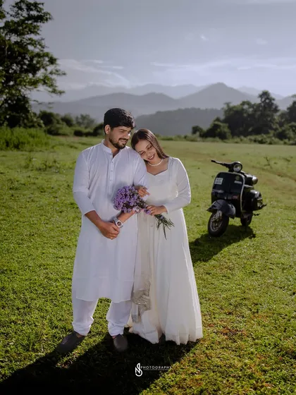 A sweet and romantic pose, with her resting her head on his shoulder. The scooter in the background adds context to their story.