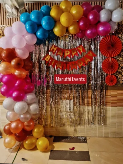 A colorful balloon arch against a silver shimmer curtain, suitable for any festive occasion.