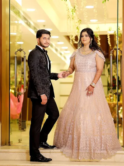 A classic and elegant pose at the entrance of the venue. The couple holds hands, ready to begin their engagement celebration.