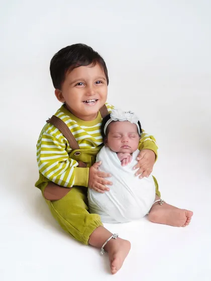A happy big brother, so proud to hold his new baby sister. I make sure to include older siblings in a way that makes them feel special and important.
