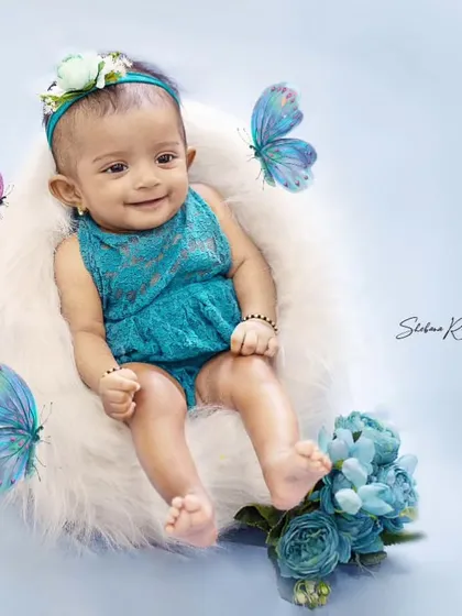 Playing with butterflies. This sitter session uses a simple, clean background with blue accents and whimsical butterflies to create a magical portrait.