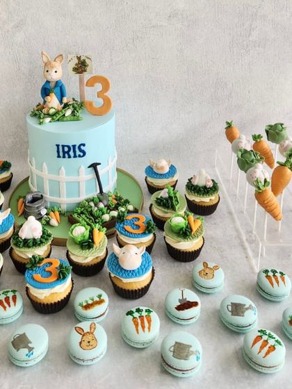 A sweet Peter Rabbit dessert table for a 3rd birthday. The cake is set in a little garden, and we made matching macarons, cupcakes, and cake pops with carrots and other garden elements.