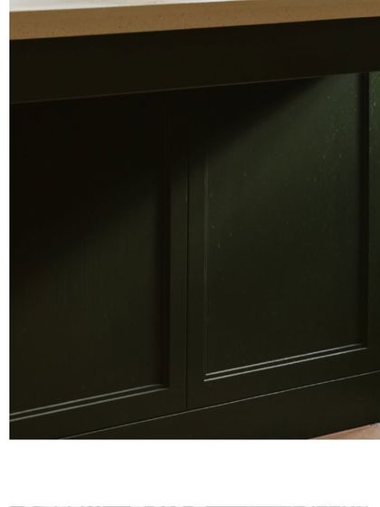 A detail of the dark green kitchen cabinetry. The classic paneling adds a touch of traditional elegance to the modern design.