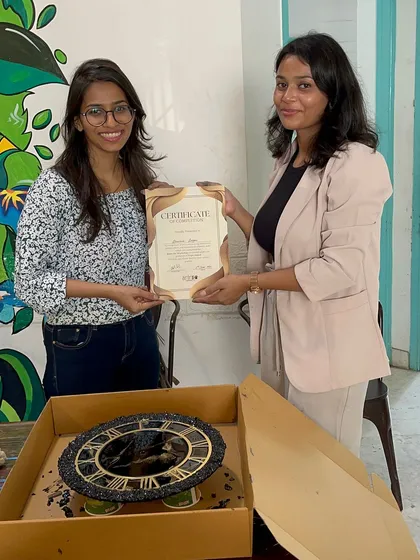 A proud artist with her certificate and her newly created vintage-style resin clock, complete with Roman numerals and a dark, stony texture.