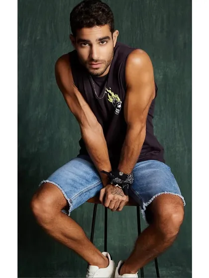 An edgy, youthful look for a men's street style collection. A graphic print muscle tee is paired with distressed denim shorts for a cool, urban vibe.