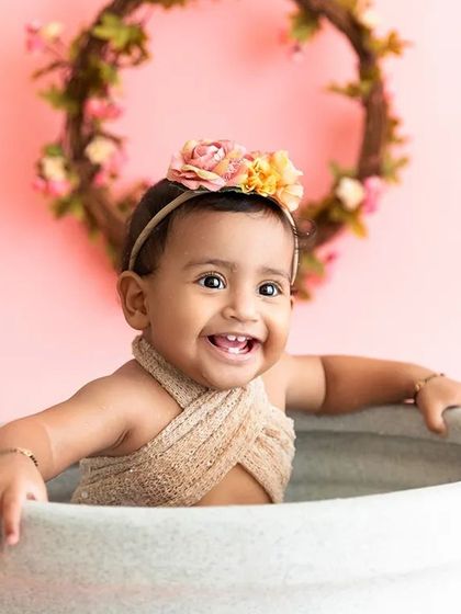 A joyful baby girl splashes happily in a tub after her cake smash, a fun "splash" part of the session.