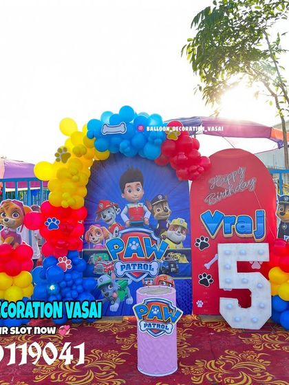 The main stage for the Paw Patrol party, set up outdoors. It features a large backdrop, character cutouts, and a light-up number '5'.