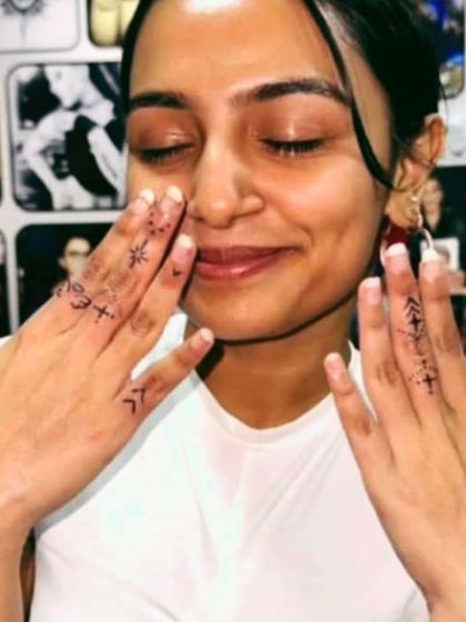Delicate finger tattoos with various small symbols.