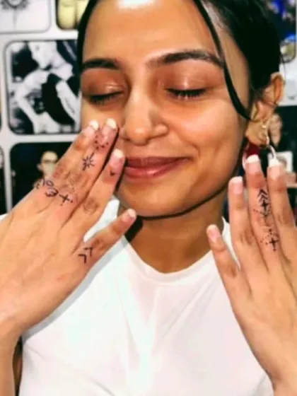 Delicate finger tattoos with various small symbols.