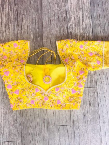 This yellow blouse is fully covered in fine threadwork and bead embroidery. The elbow-length sleeves and neckline have a consistent, neat pattern.