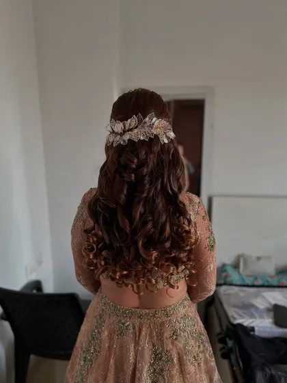 A close-up of the soft curls half-updo with the leafy accessory, showing the texture and detail.