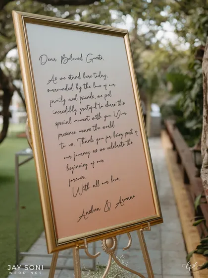 A detailed shot of the welcome note to guests, written in beautiful calligraphy on an ombre peach and white background, framed in gold.