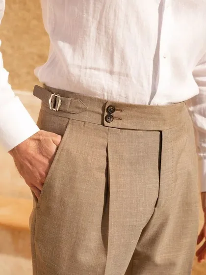 A close-up of our tailored trousers, featuring a Gurkha-style waistband with double buttons and side adjusters. This detail offers a unique look and a secure, comfortable fit.
