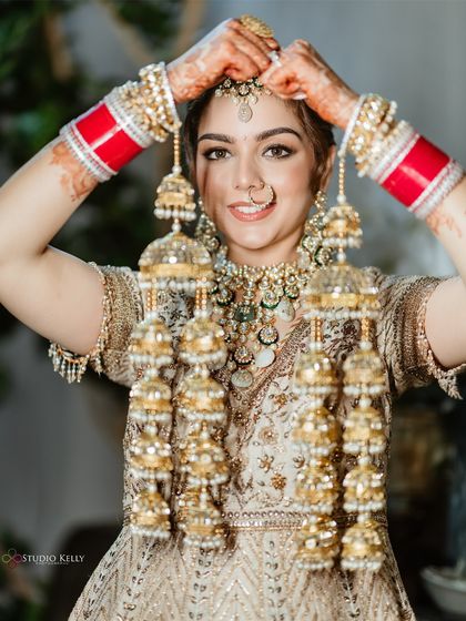 The bride joyfully shows off her traditional Kalire, a significant accessory in a Punjabi wedding, during her Bangkok celebration.