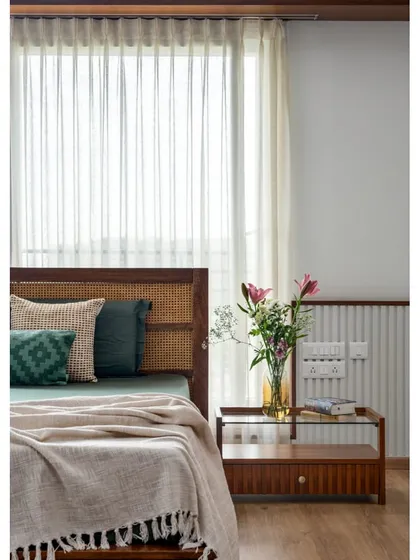 Detail of the bedside in 'Vasudhalayah', showing a custom side table with a glass top and fluted wood detailing.
